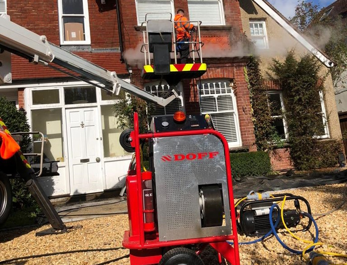 Man using a doff machine to jet wash the outside of a property